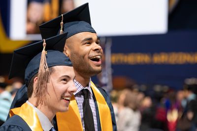Two students smiling at their graduation ceremony.
