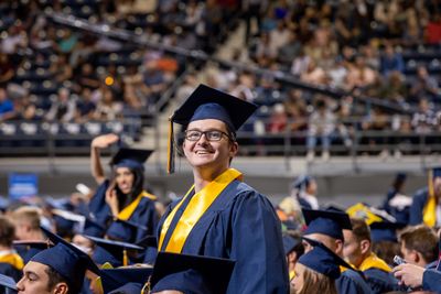A smiling NAU student standing at commencement.