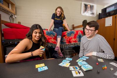 Three students playing cards in a dorm room.
