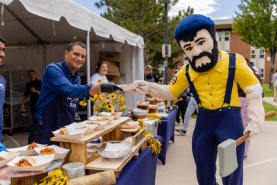 NAU President, Dr. José Luis Cruz Rivera, serving food to NAU's mascot, Louie the Lumberjack.