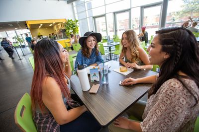 A group of student talk over food in campus dining.