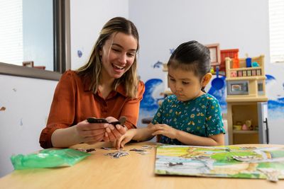 A student instructor sits with a young student in a classroom.