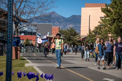 NAU students walking, skating, and biking on a pretty day on the Flagstaff campus.