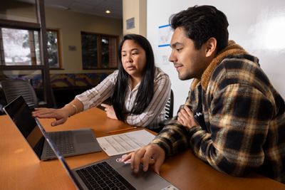 Adviser talking to a student and sharing information on a laptop.
