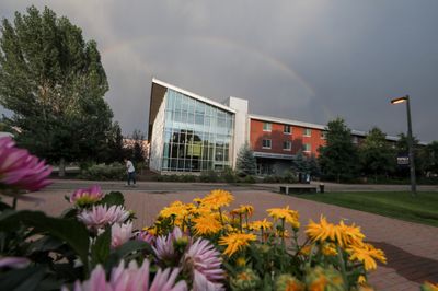 The outside of Calderon Hall, a residential space, surrounded by trees and flowers on the NAU campus.