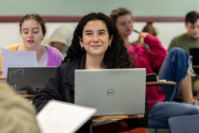 An NAU history student smiles while taking notes on her laptop.