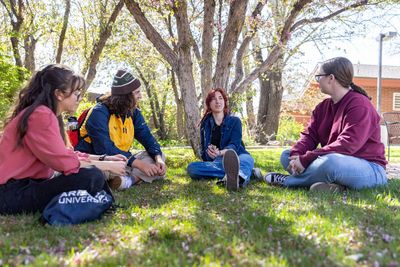 NAU students sit on a grassy field.