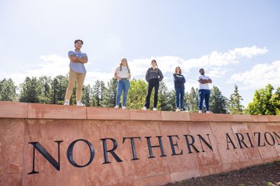 Students standing on a wall that says "Northern Arizona University".