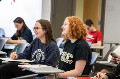 NAU students smile while listing to a lecture on international affairs.