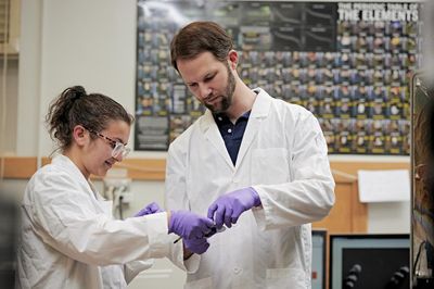N A U physics students wearing lab coats work in a lab.
