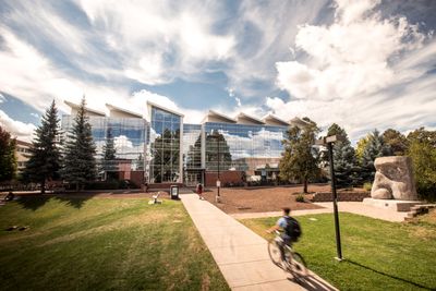 Student rides a bike on NAU Flagstaff mountain campus in front of the Engineering building.