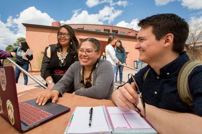 Three NAU indigenous studies students smile while working together on campus.